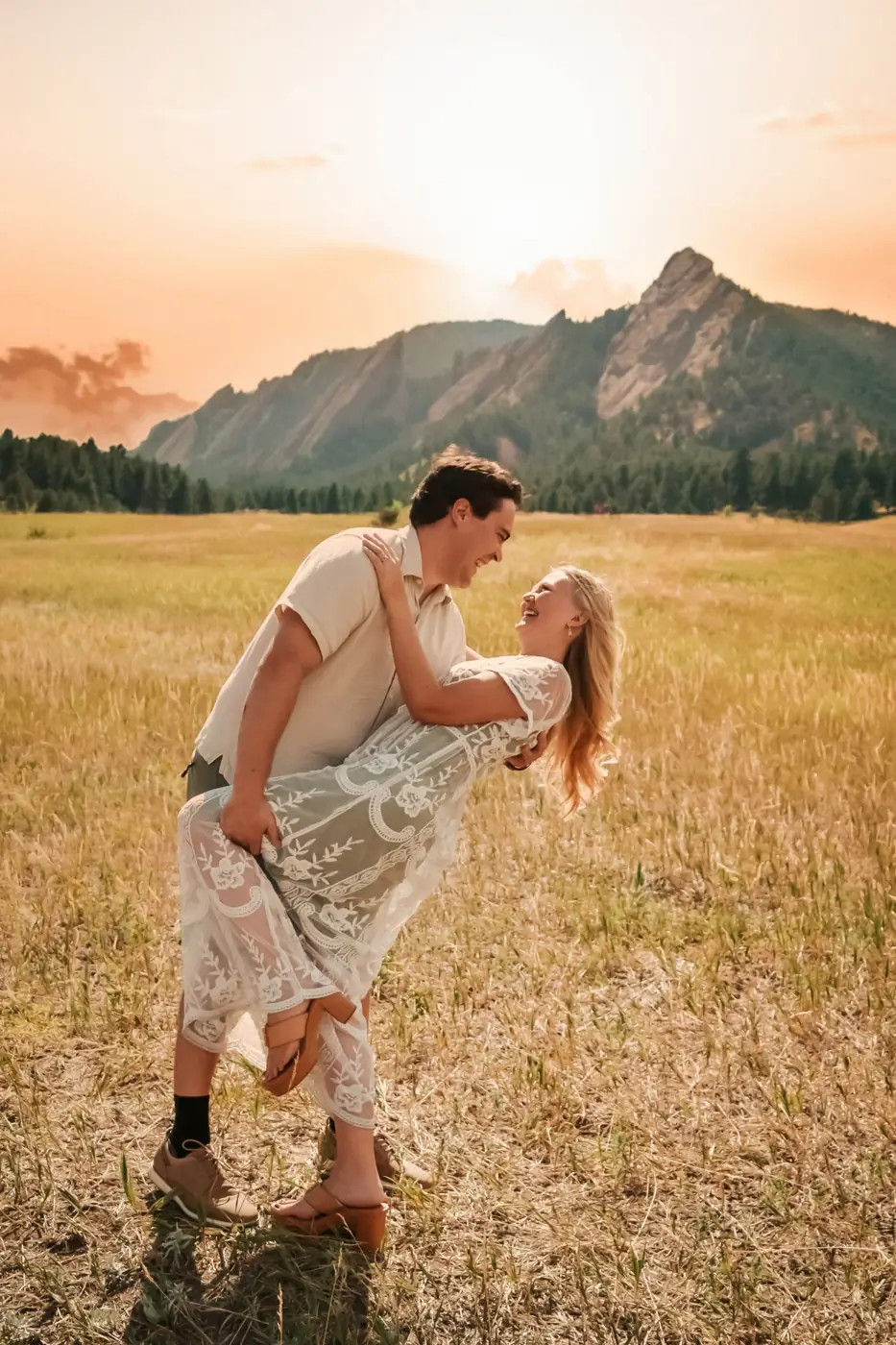 He dips her laughing in a lace dress in a golden meadow