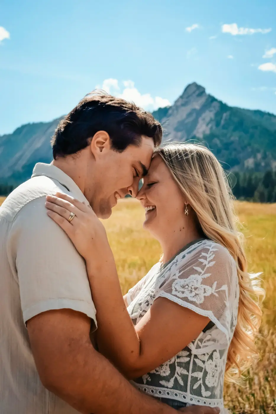 Couple touching foreheads and laughing with the mountains behind