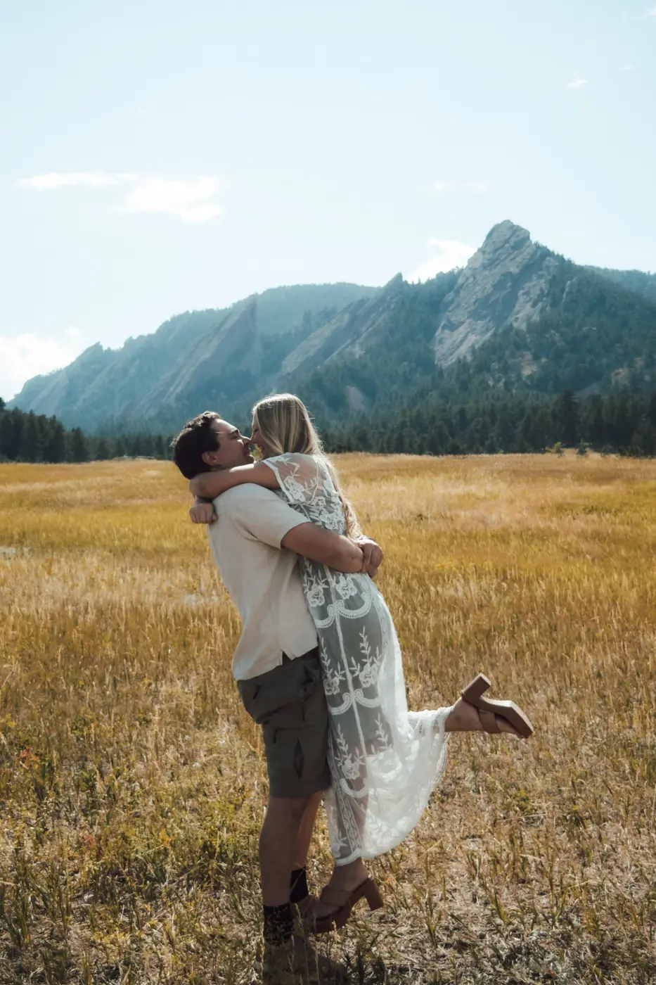 He lifts her in a lace dress, nose to nose, in a golden meadow