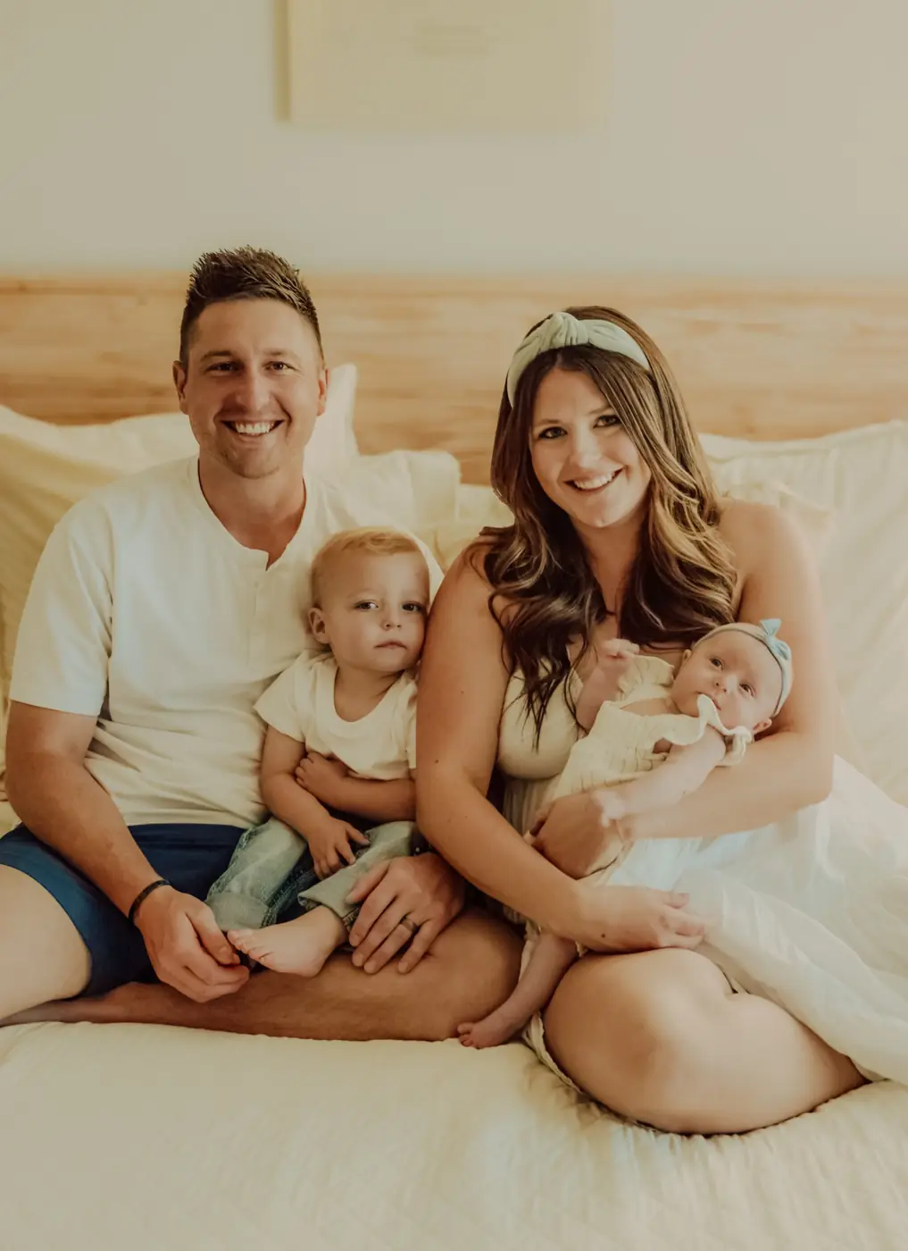 Parents on a bed with their toddler and newborn daughter