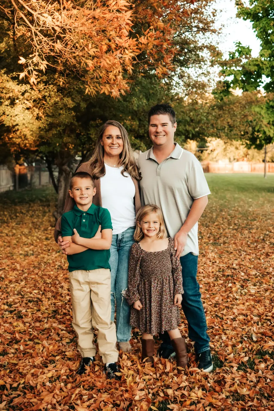 Family of four standing in fallen autumn leaves