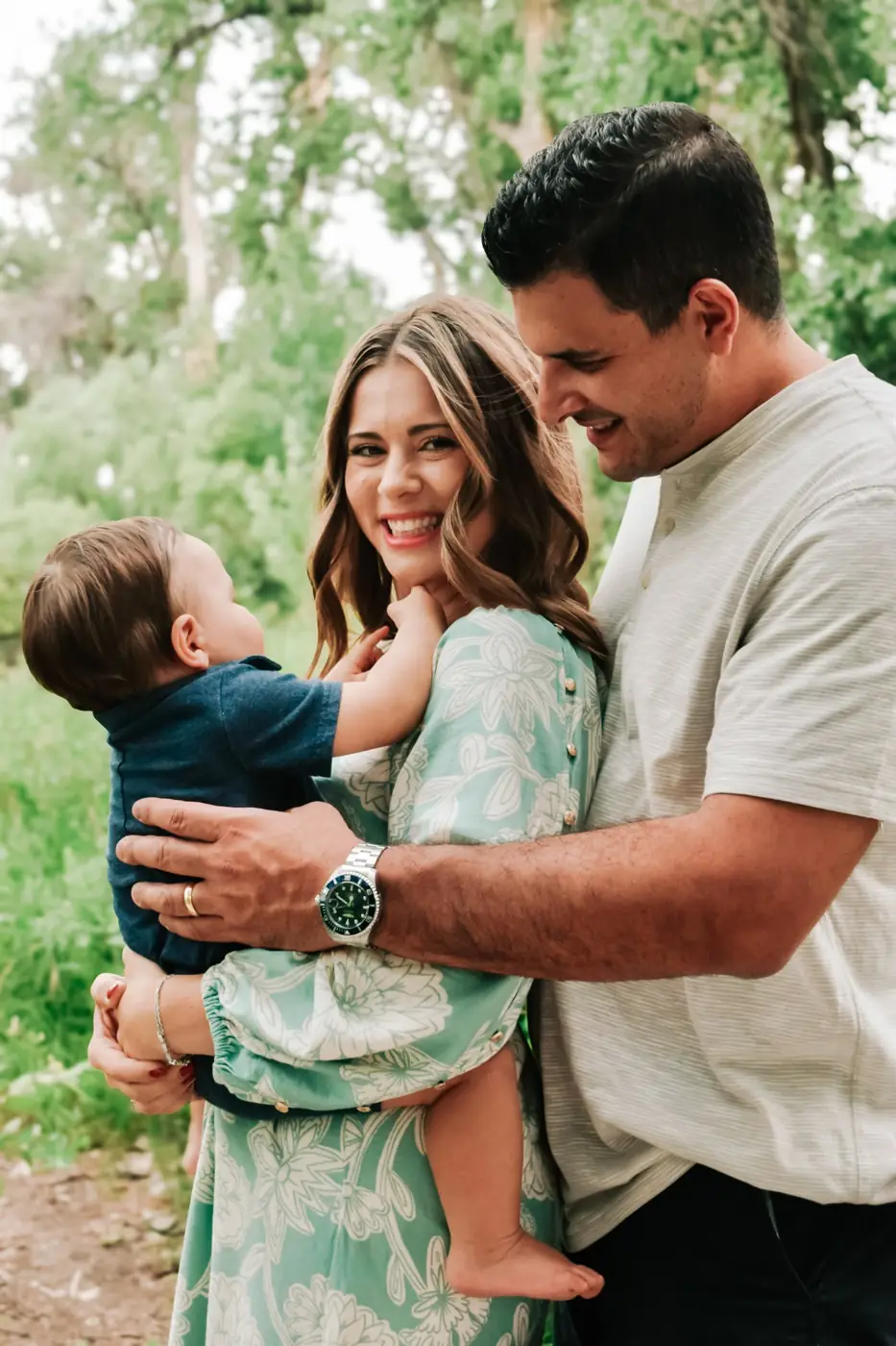 Mom smiling at the camera holding her baby while dad looks on