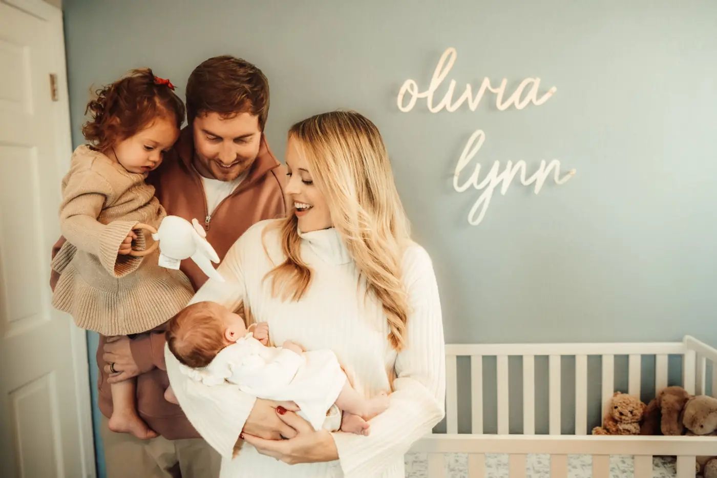 Parents holding their toddler and newborn in the nursery