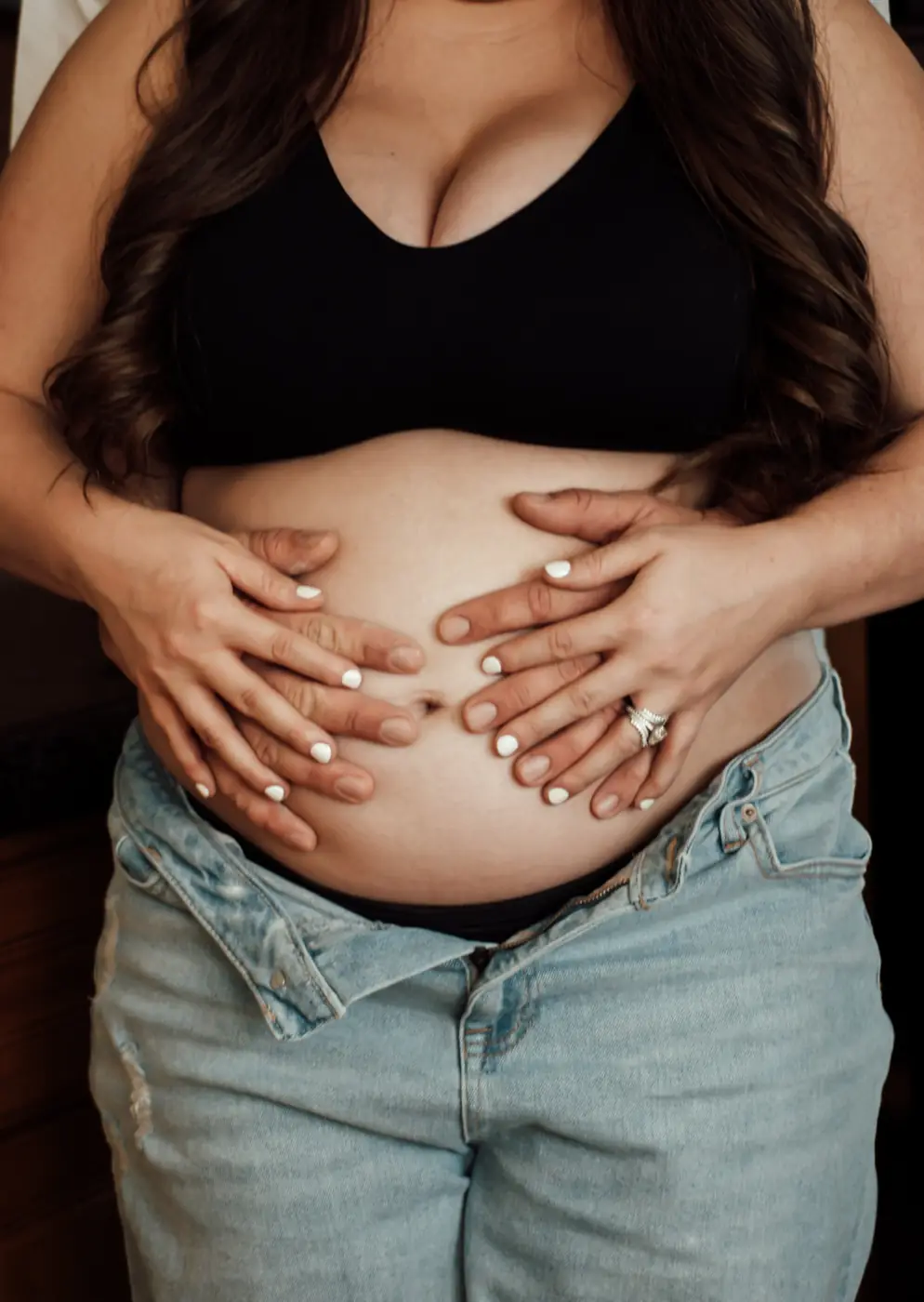 Close-up of a couple’s hands together on an expecting belly