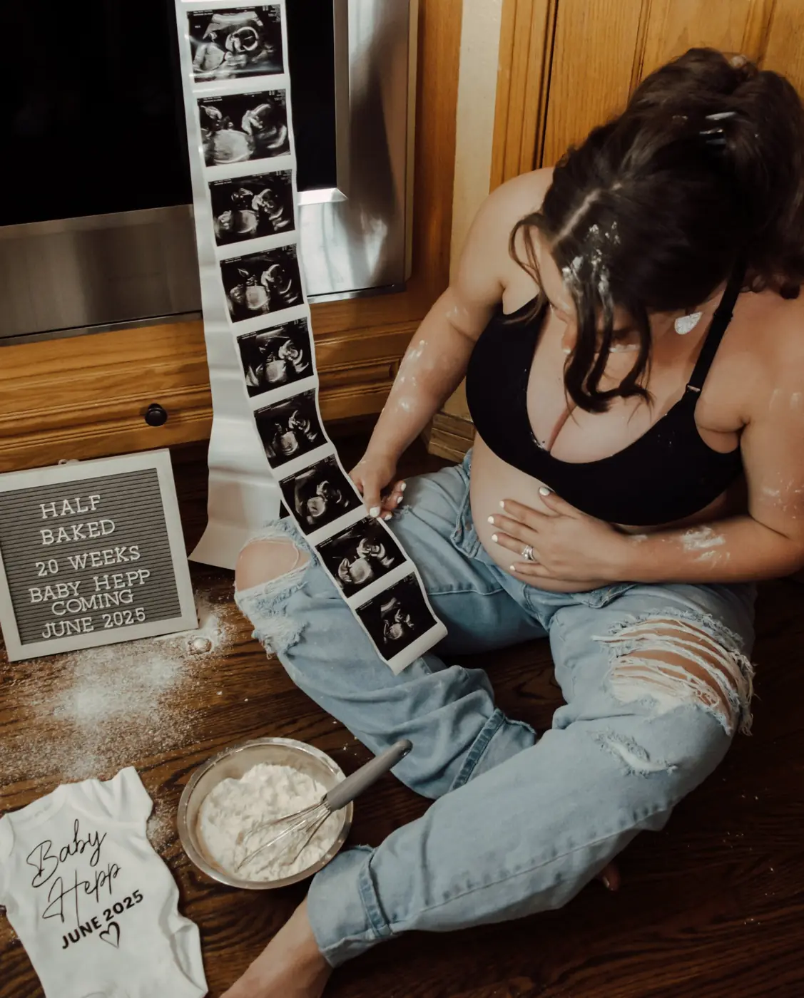 Expecting mother sitting on the kitchen floor looking at her ultrasound strip
