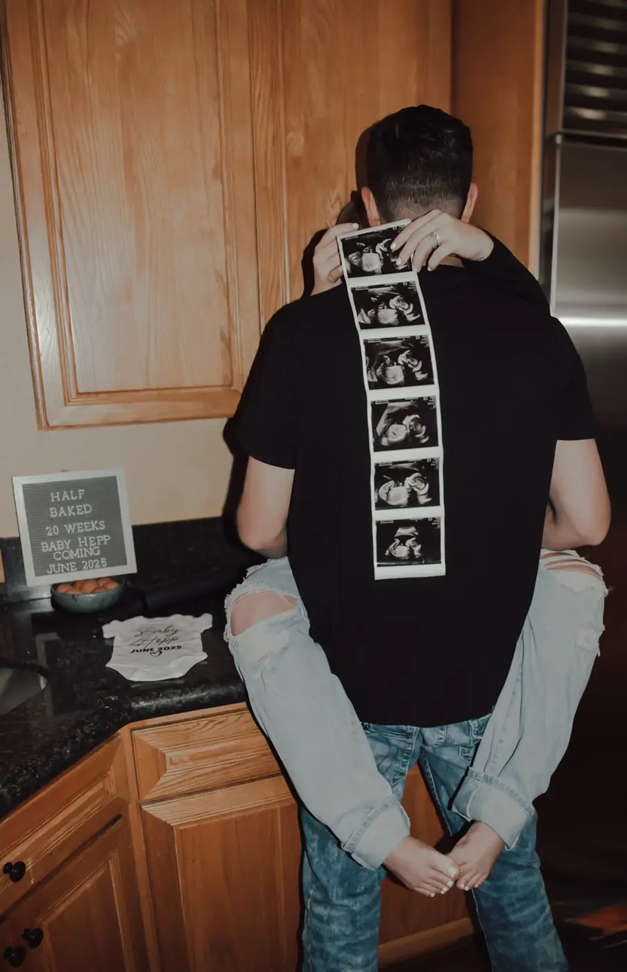 Couple embracing in the kitchen with an ultrasound strip down his back