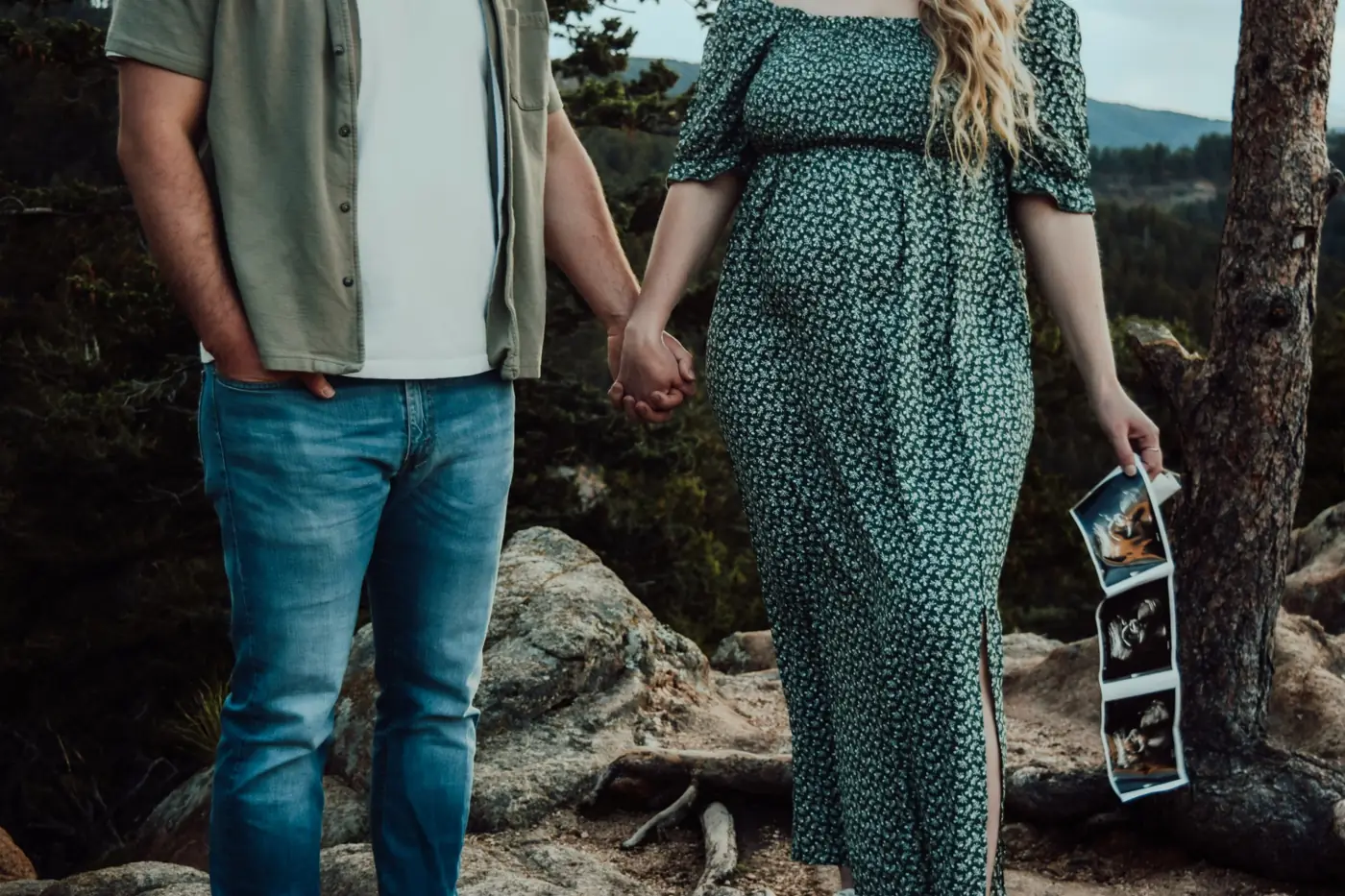 Couple holding hands at a mountain overlook with an ultrasound strip