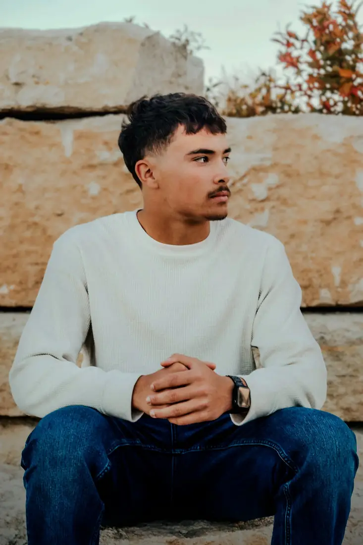 Senior portrait in profile against a stone wall