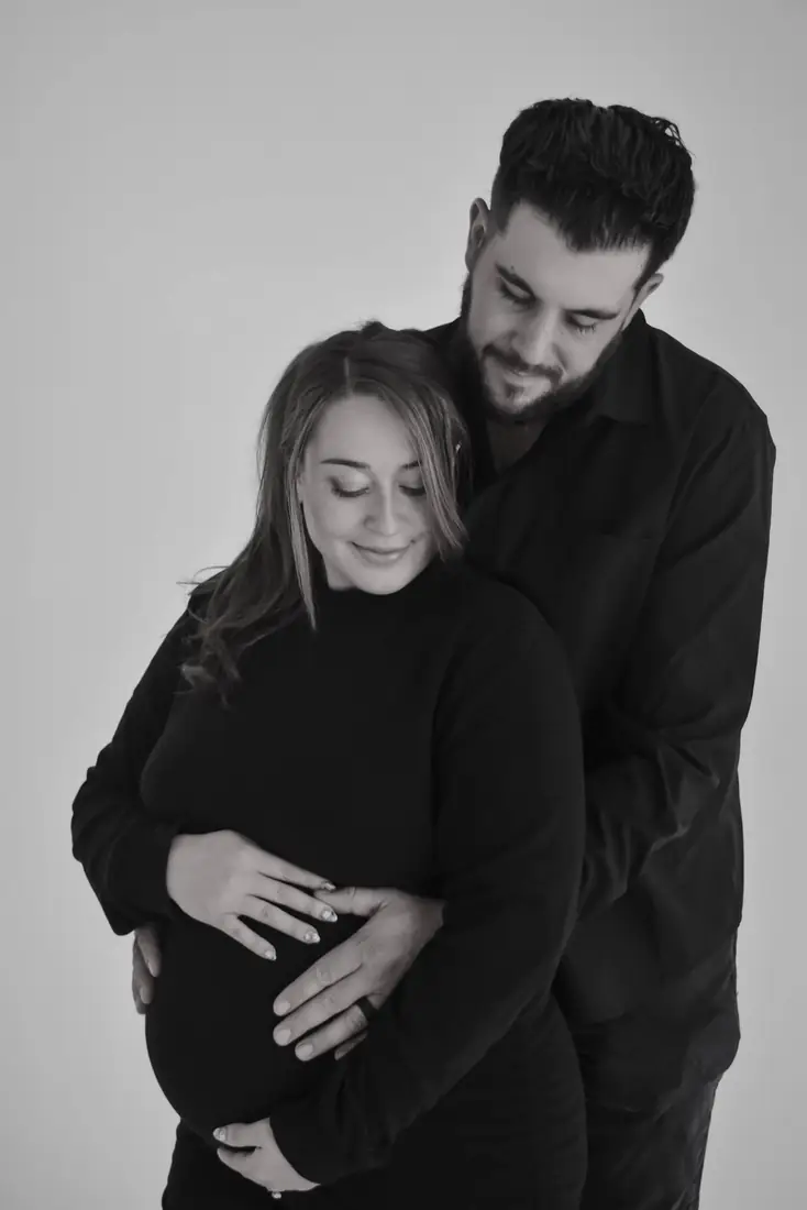 Black-and-white studio maternity portrait of a couple embracing
